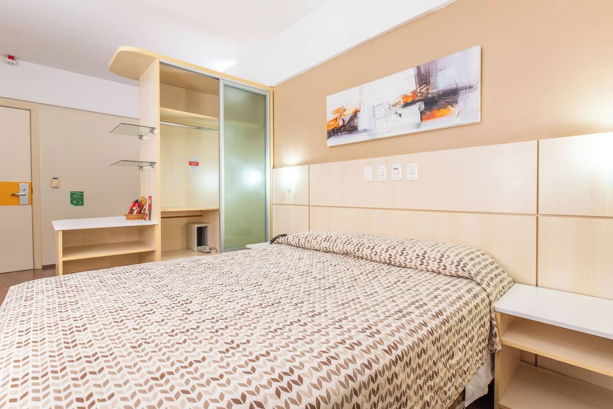 Une chambre d’hôtel avec un lit, un bureau et une armoire.
