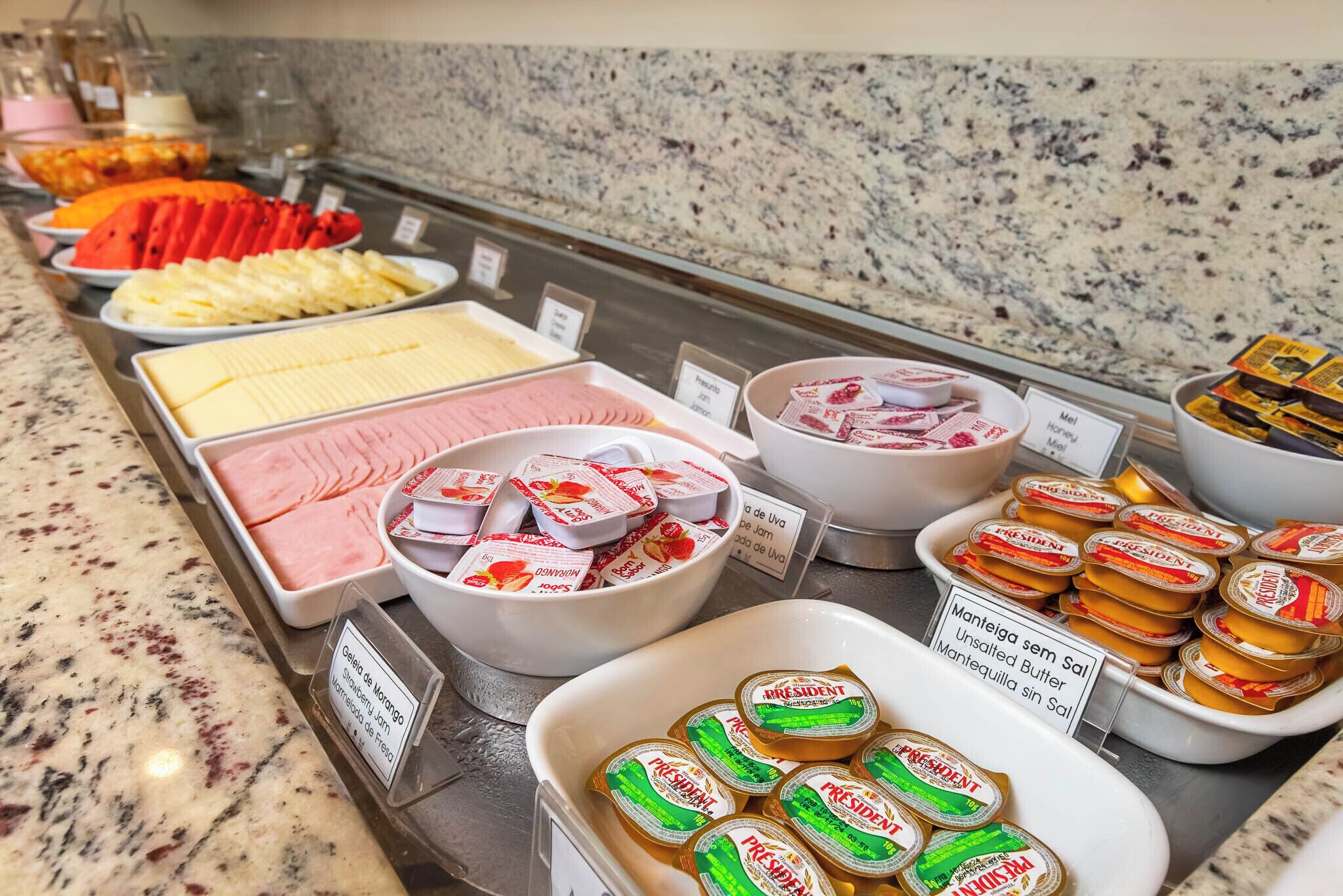 A buffet with various food items including fruits, cheeses, and packaged desserts.