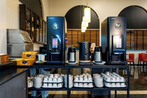 A coffee station with multiple coffee machines and a variety of coffee cups and plates.