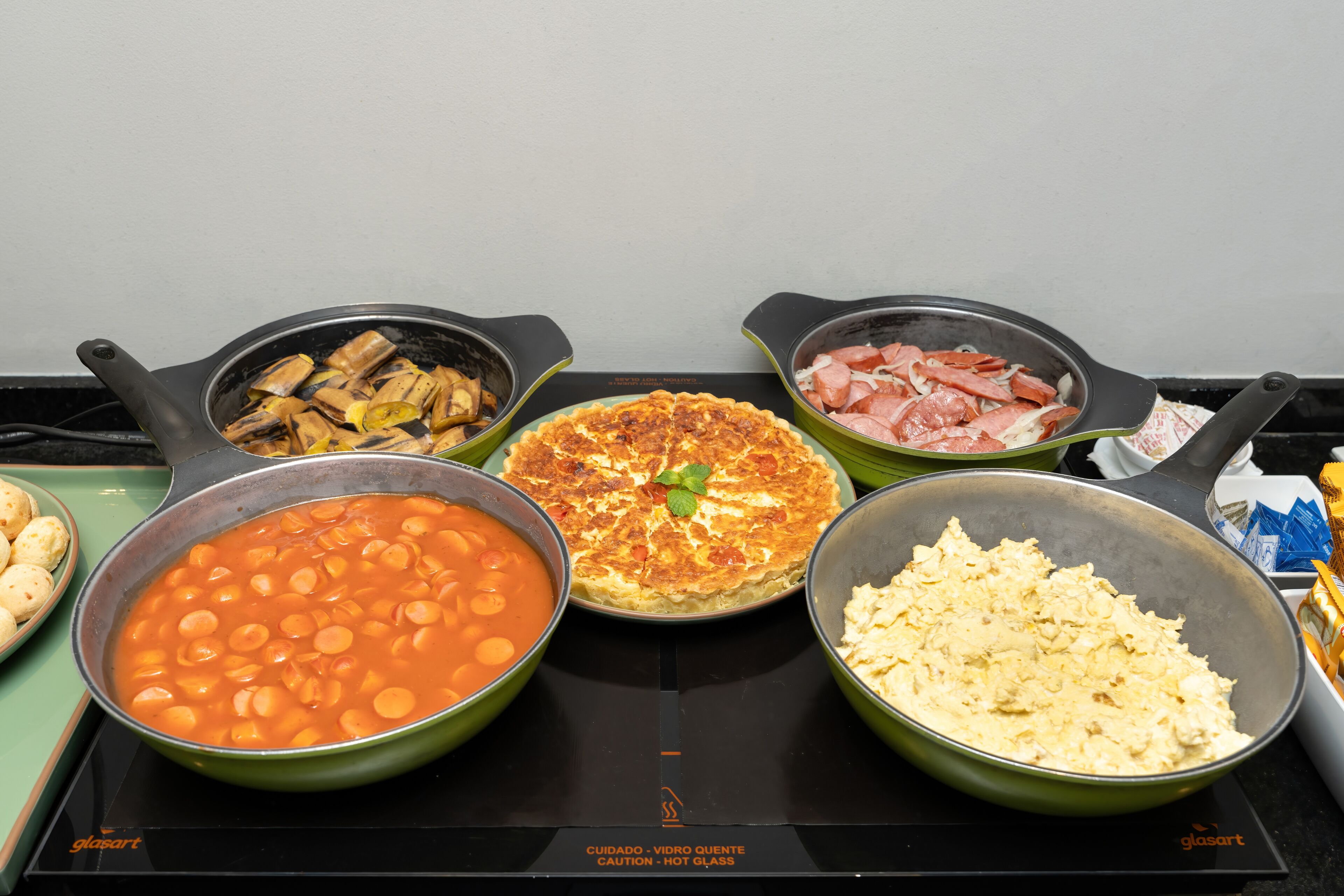 A variety of dishes on a stovetop, including a pot of beans, a skillet with vegetables, a pan with meat, a pie, and a bowl of scrambled eggs.