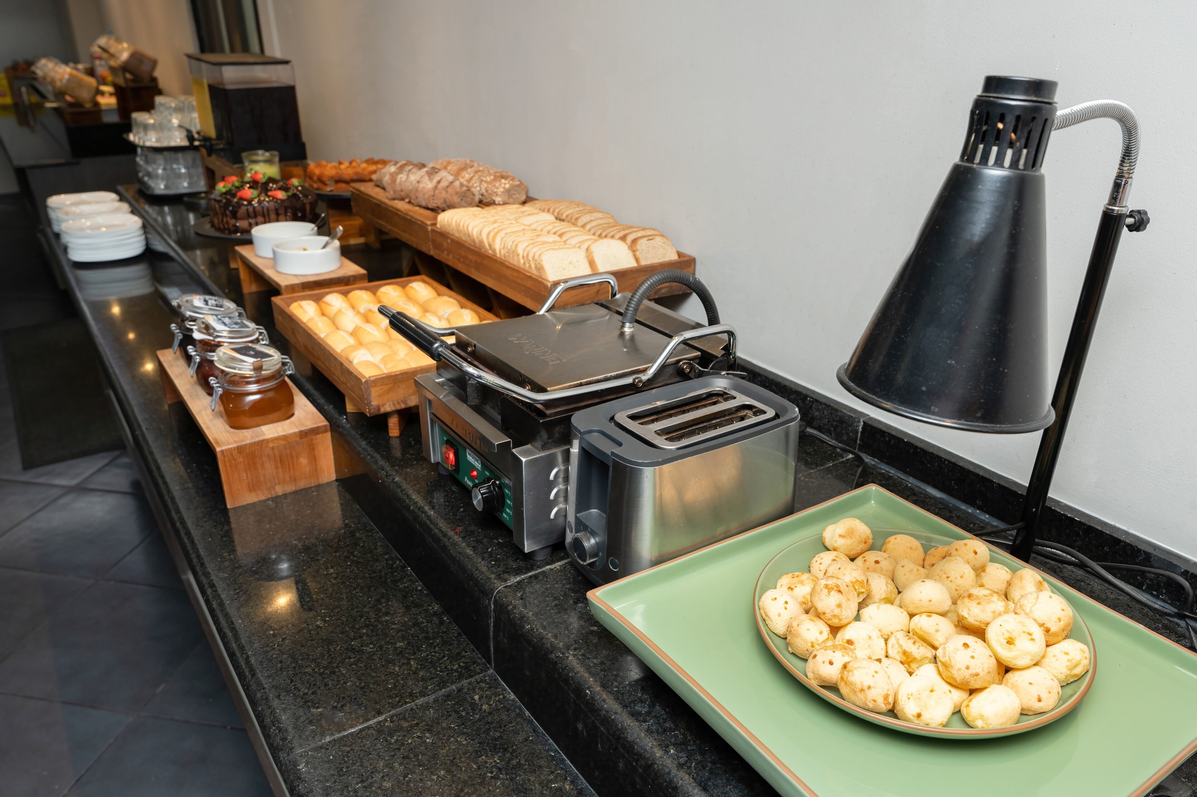 A buffet setup with various food items, including bread, pastries, and a plate of cheese balls.