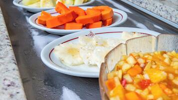 A buffet with various dishes including fruits and vegetables.