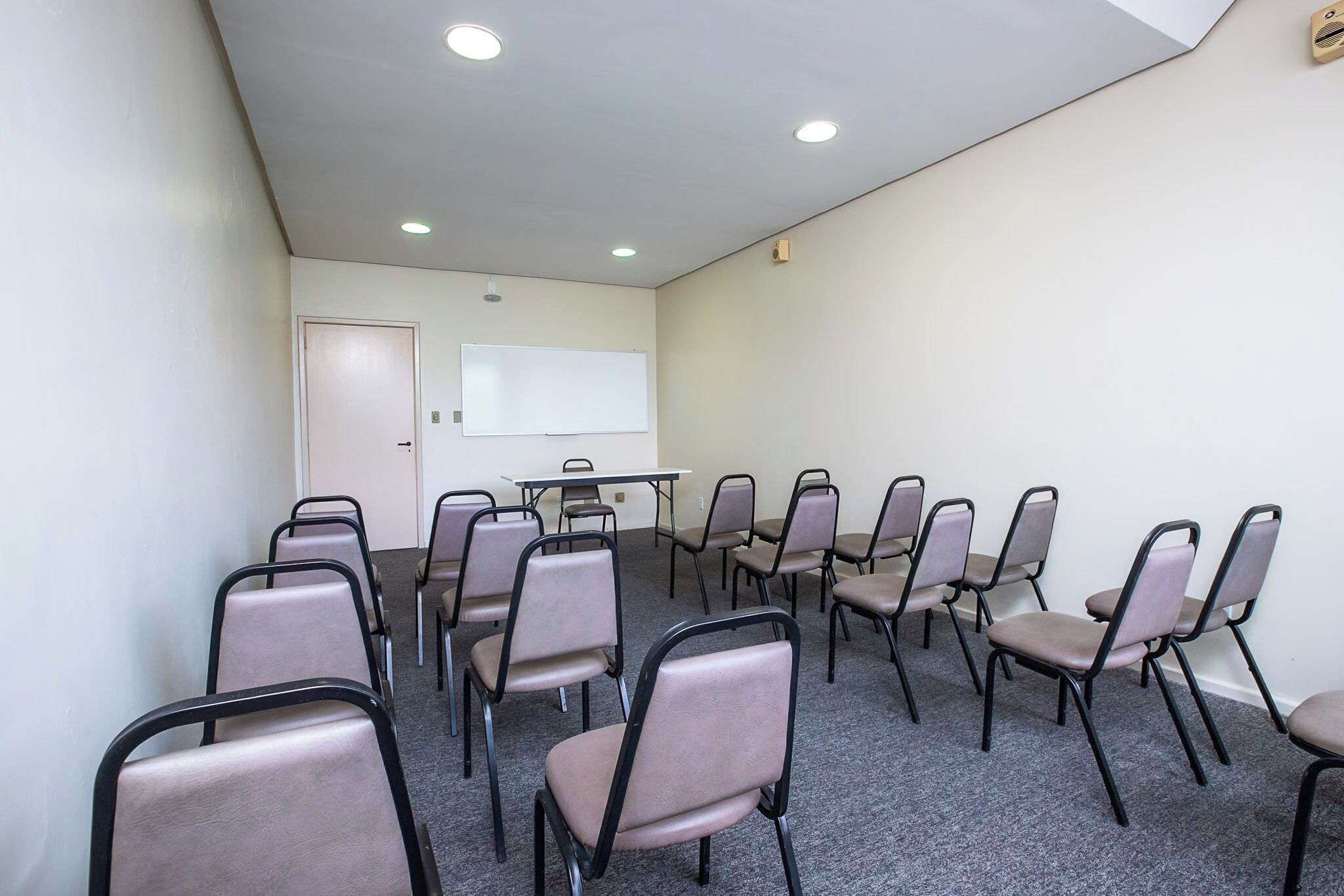 A conference room with a whiteboard, a table, and multiple chairs arranged for meetings.