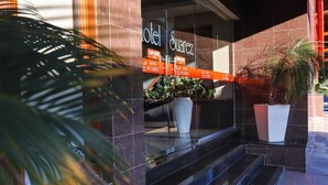 A hotel entrance with a sign reading 'Hotel Suarez,' steps leading up to the entrance, and potted plants. - Hotel Suárez Campo Bom (Campo Bom)