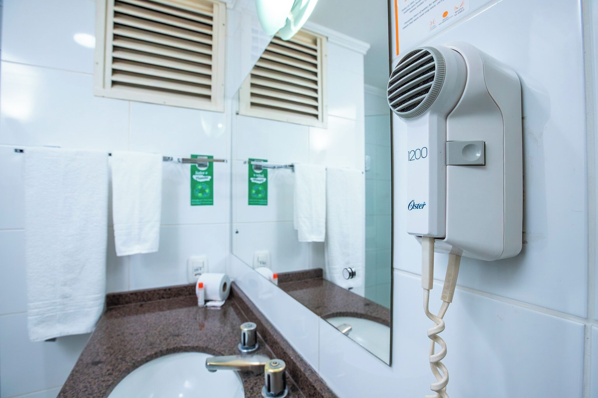 A bathroom with a sink, mirror, towel rack, and a hair dryer mounted on the wall.