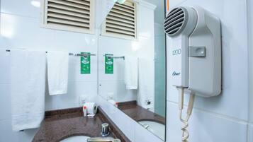 A bathroom with a sink, mirror, towel rack, and a hair dryer mounted on the wall.