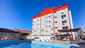 A hotel with a swimming pool, outdoor seating, and a red and white building. - Hotel Suárez Campo Bom (Campo Bom)