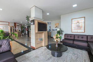 Un hall d’entrée moderne doté d’un comptoir de réception, d’un espace salon et d’un téléviseur à écran plat.