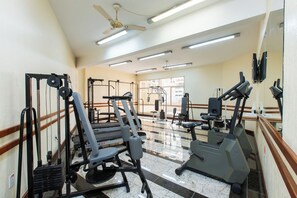 A gym with exercise equipment, a ceiling fan, and large windows.