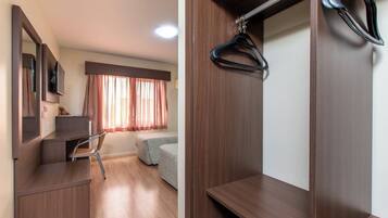 Un dormitorio con escritorio, una silla, una cama y un armario.
