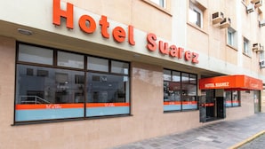 Een gebouw met een bord waarop 'Hotel Suarez' staat en grote ramen.