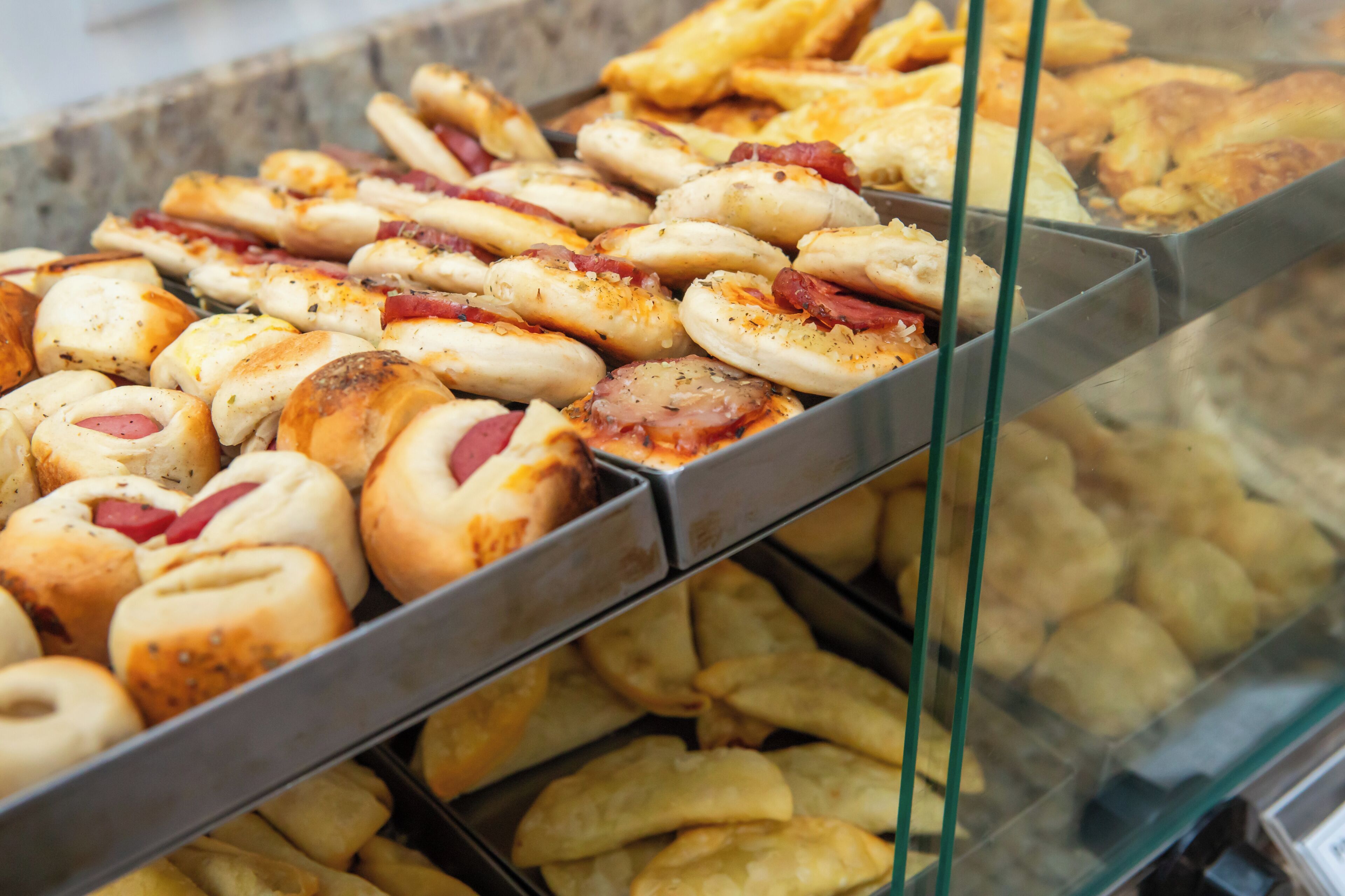 A display case with various baked goods, including rolls and pastries.