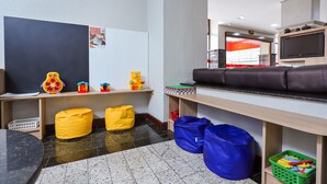 A children's play area with a whiteboard, toys, bean bags, and a TV. - Hotel Suárez São Leopoldo (Sao Leopoldo)