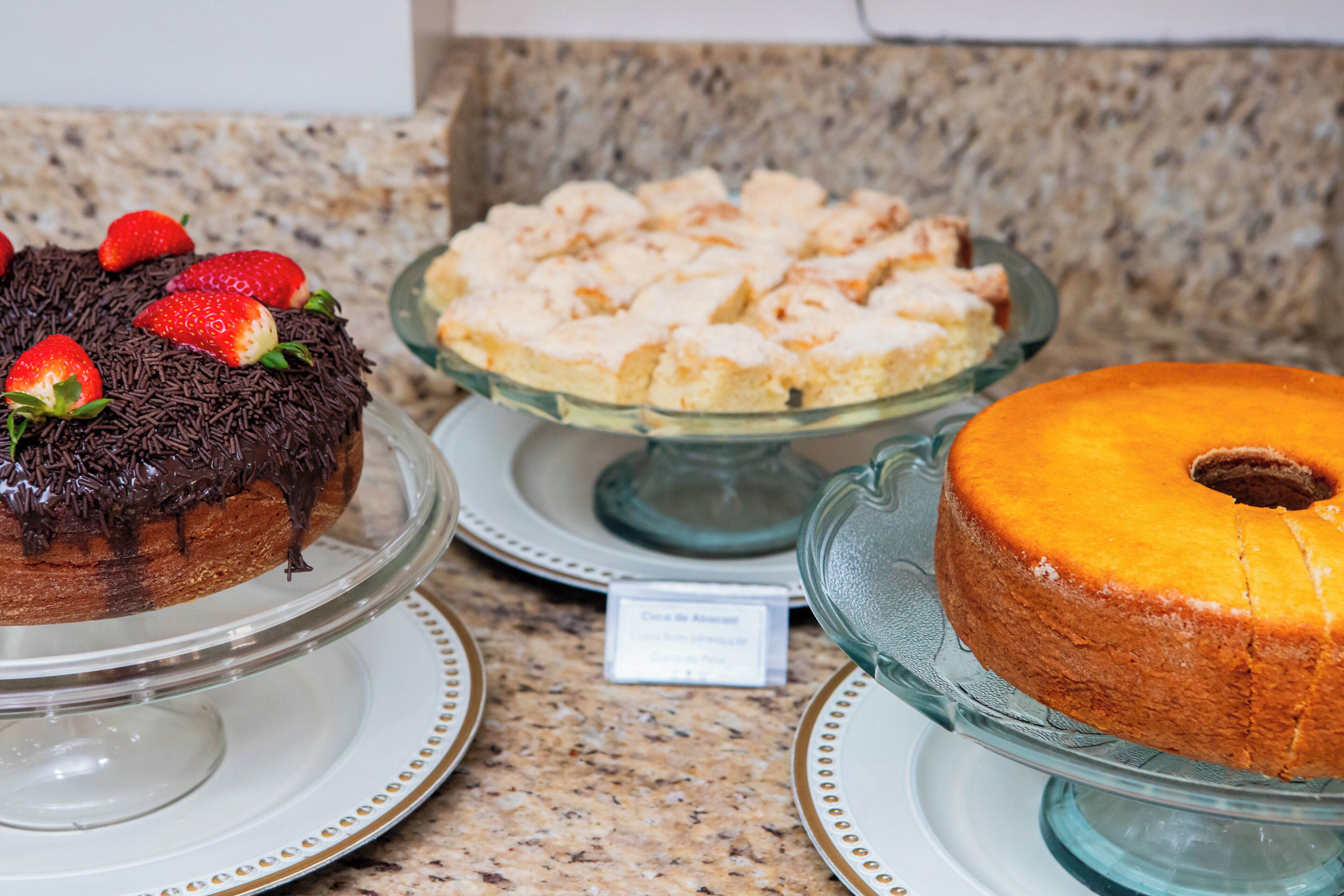 Un présentoir à desserts avec divers gâteaux et pâtisseries disposés sur des supports en verre.