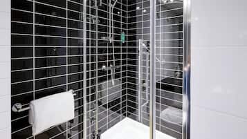 Une salle de bain moderne avec des murs recouverts de carreaux noirs, une douche en verre et une serviette blanche posée sur un porte-serviettes.