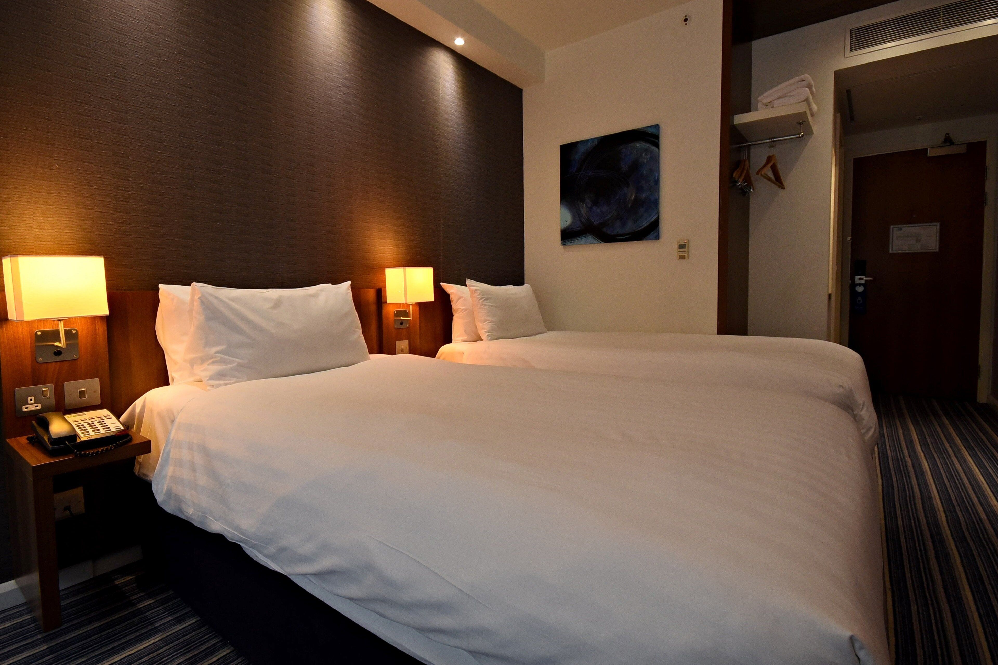 Ein Hotelzimmer mit einem großen Bett, zwei Nachttischlampen, einem Telefon und einem Bild an der Wand.