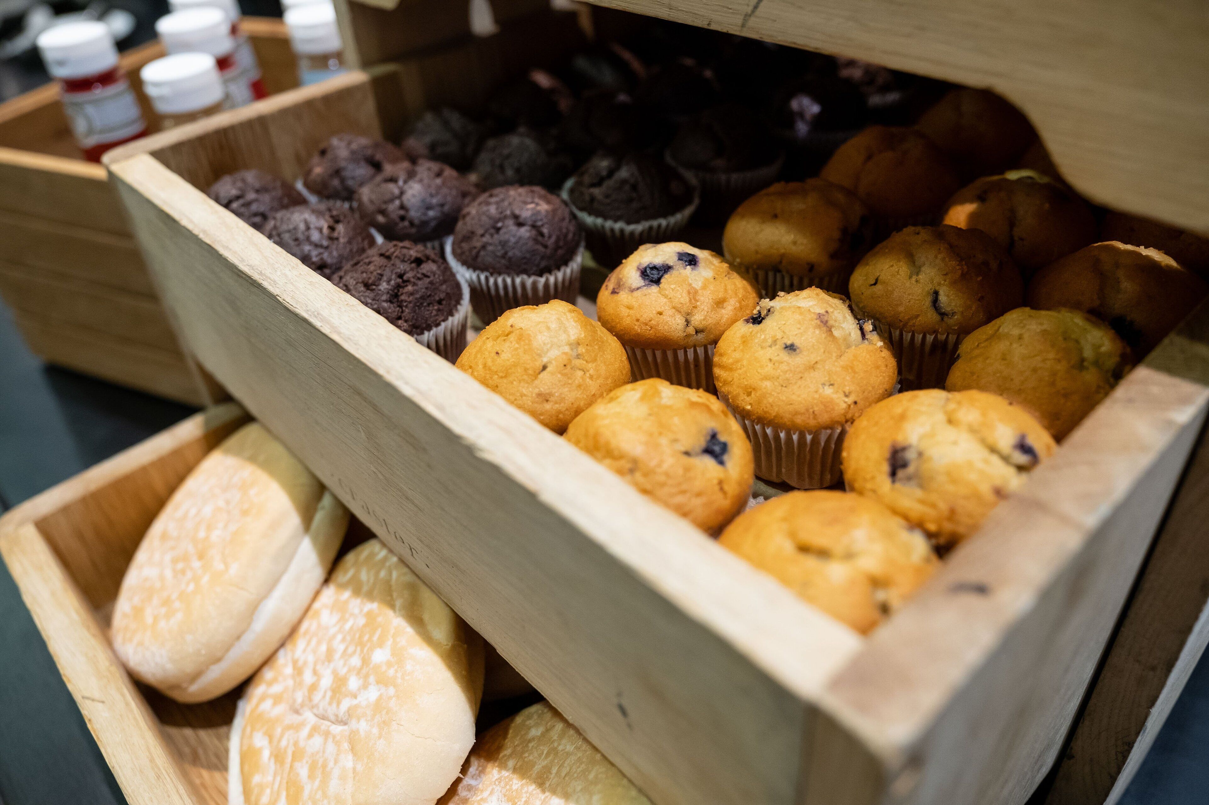 Una caja de madera llena de muffins y pasteles.