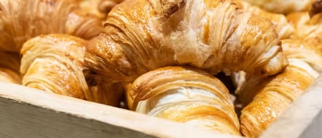 A wooden box containing various baked goods, including croissants and muffins.