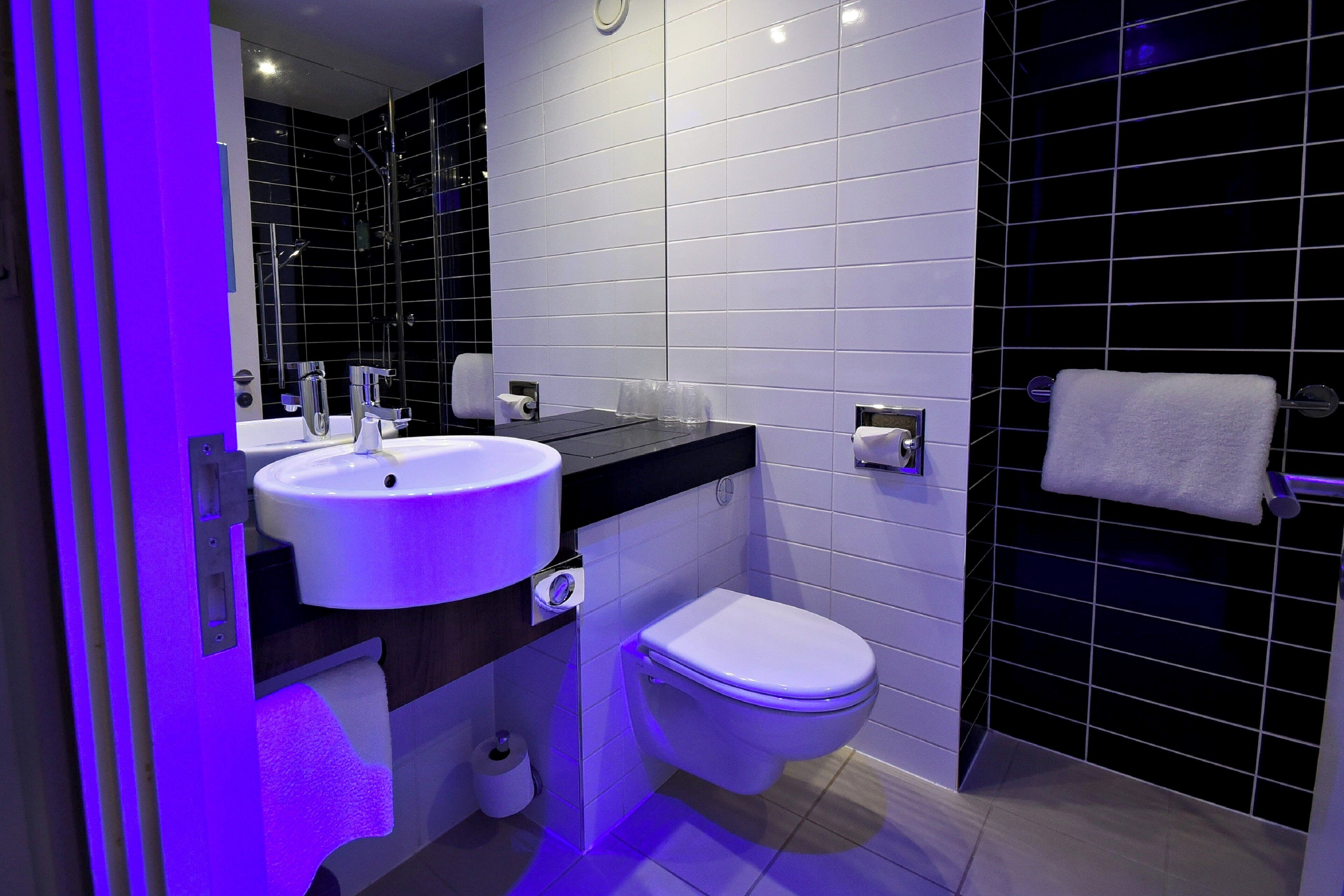 A modern bathroom with a white sink, a toilet, and a mirror.
