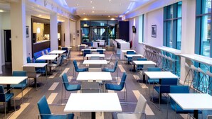 A modern dining area with multiple tables and chairs, large windows, and a view of the outside. - Holiday Inn Express Manchester City Centre Arena by IHG (Manchester)