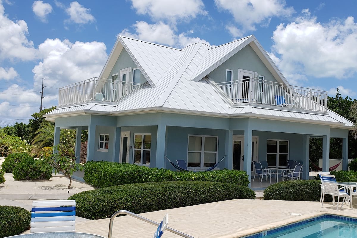 A two-story building with a balcony, a swimming pool, and outdoor seating.