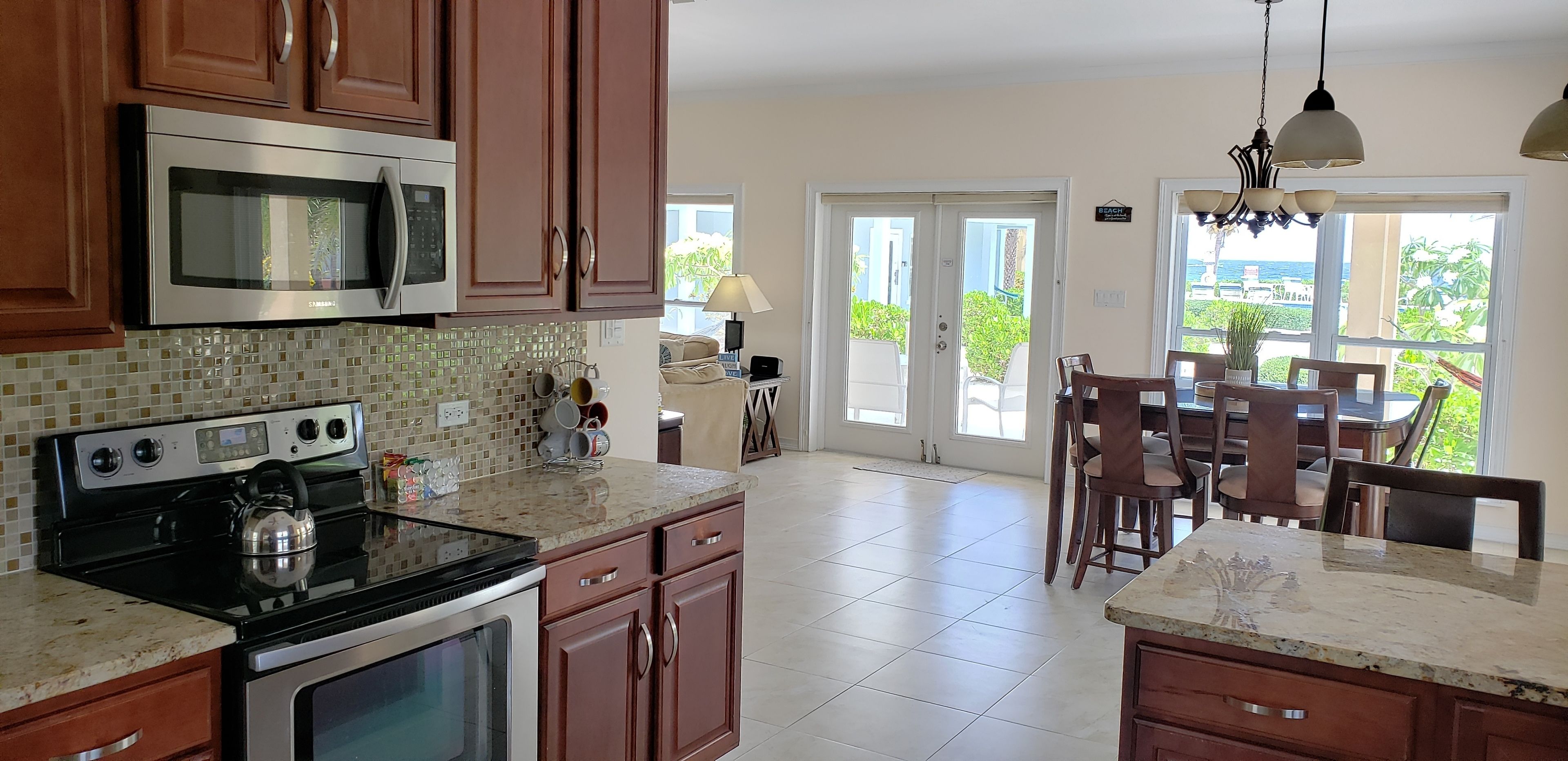 A kitchen with wooden cabinets, stainless steel appliances, and a dining area with a view.