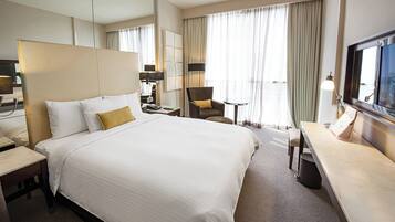 Een hotelkamer met een groot bed, een bureau, een stoel en een televisie.