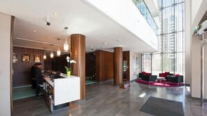 Eine moderne Lobby mit einer Rezeption, einer Sitzecke und großen Fenstern.