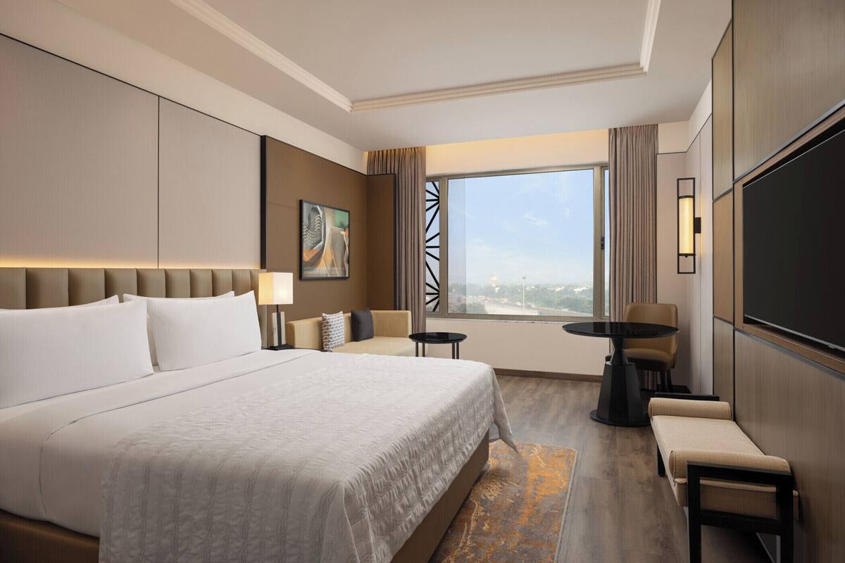 Une chambre d’hôtel avec un grand lit, une petite table ronde, un canapé et un téléviseur.