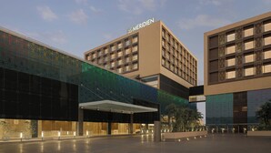 A hotel with a modern facade, a prominent 'MERIDIEN' sign, and a covered entrance area. - Le Meridien Surat (Surat)