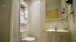 A small bathroom with a toilet, a sink, and a mirror. - The Horizon Hotel (Baku)