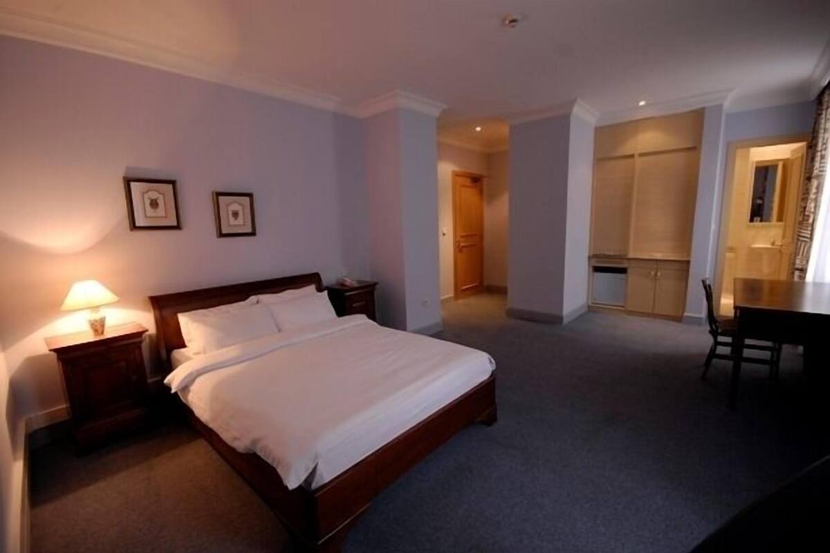 A hotel room with a bed, bedside tables, a desk, and a chair.
