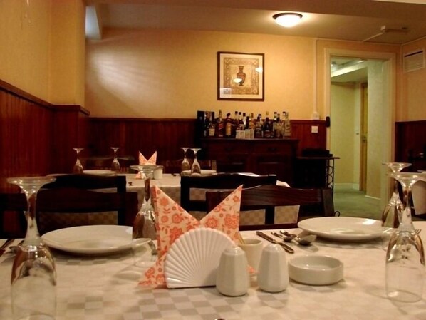A restaurant with tables set for dining, a bar area with bottles, and a framed picture on the wall.