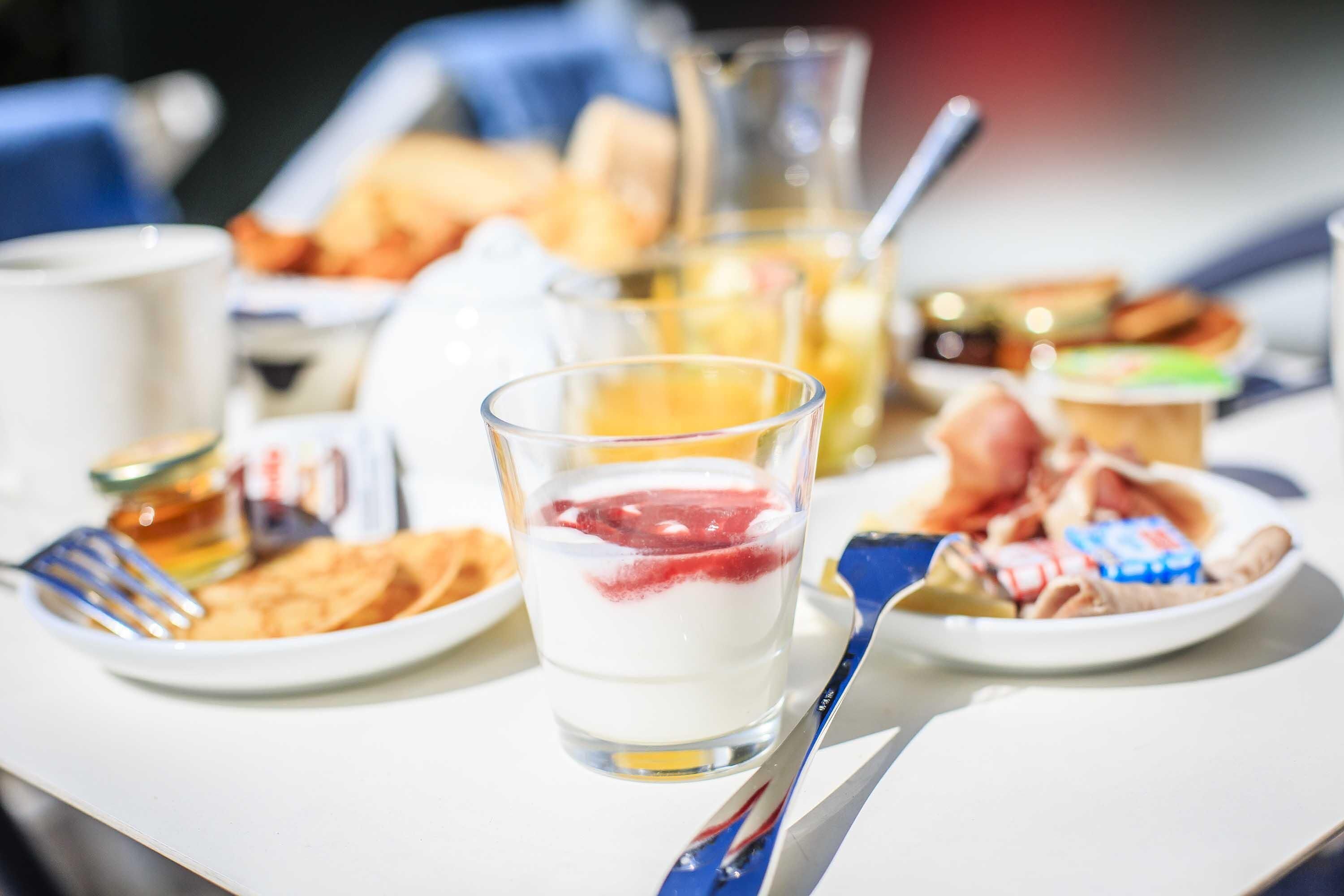 Ein Frühstückstisch mit Tellern voller Speisen, einem Glas Milch und einem Saftkrug.