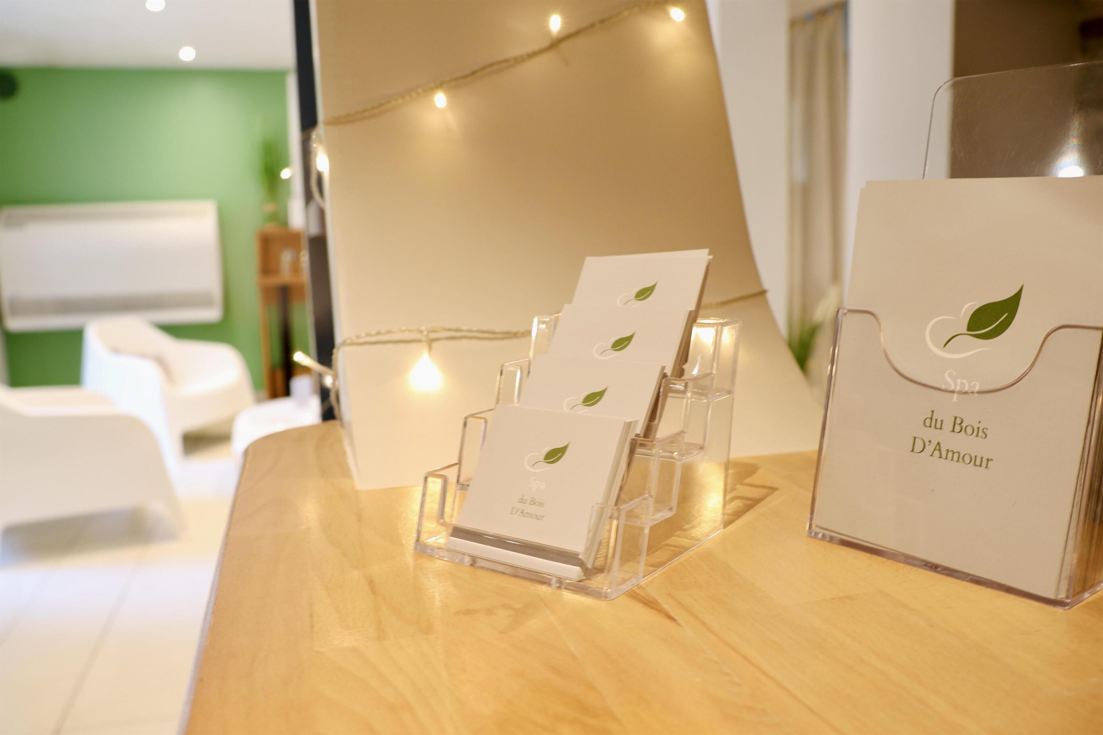 A reception desk with a card holder displaying cards and a bag with 'Spa du Bois D'Amour' text.