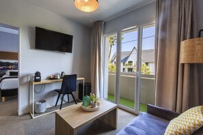 Une chambre d’hôtel avec un lit, un bureau et une chaise, une télévision et un balcon avec vue.