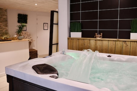 Un espace bien-être comprenant un jacuzzi, un lambris en bois et un mur carrelé avec un motif en quadrillage.. Best Western Hotel Garden & Spa