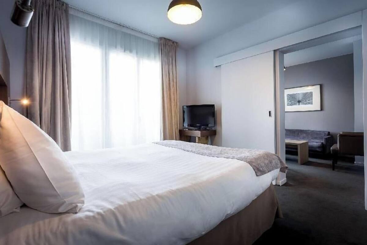 A hotel room with a large bed, a television, a sofa, and a desk.