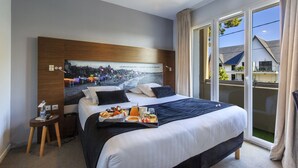 A hotel room with a large bed, a cityscape poster on the wall, a tray with breakfast items, and a view of the outside balcony. - Best Western Hotel Garden & Spa (La Baule-Escoublac)