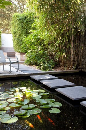 A serene garden with a pond, stone steps, and a bench. - Best Western Hotel Garden & Spa (La Baule-Escoublac)