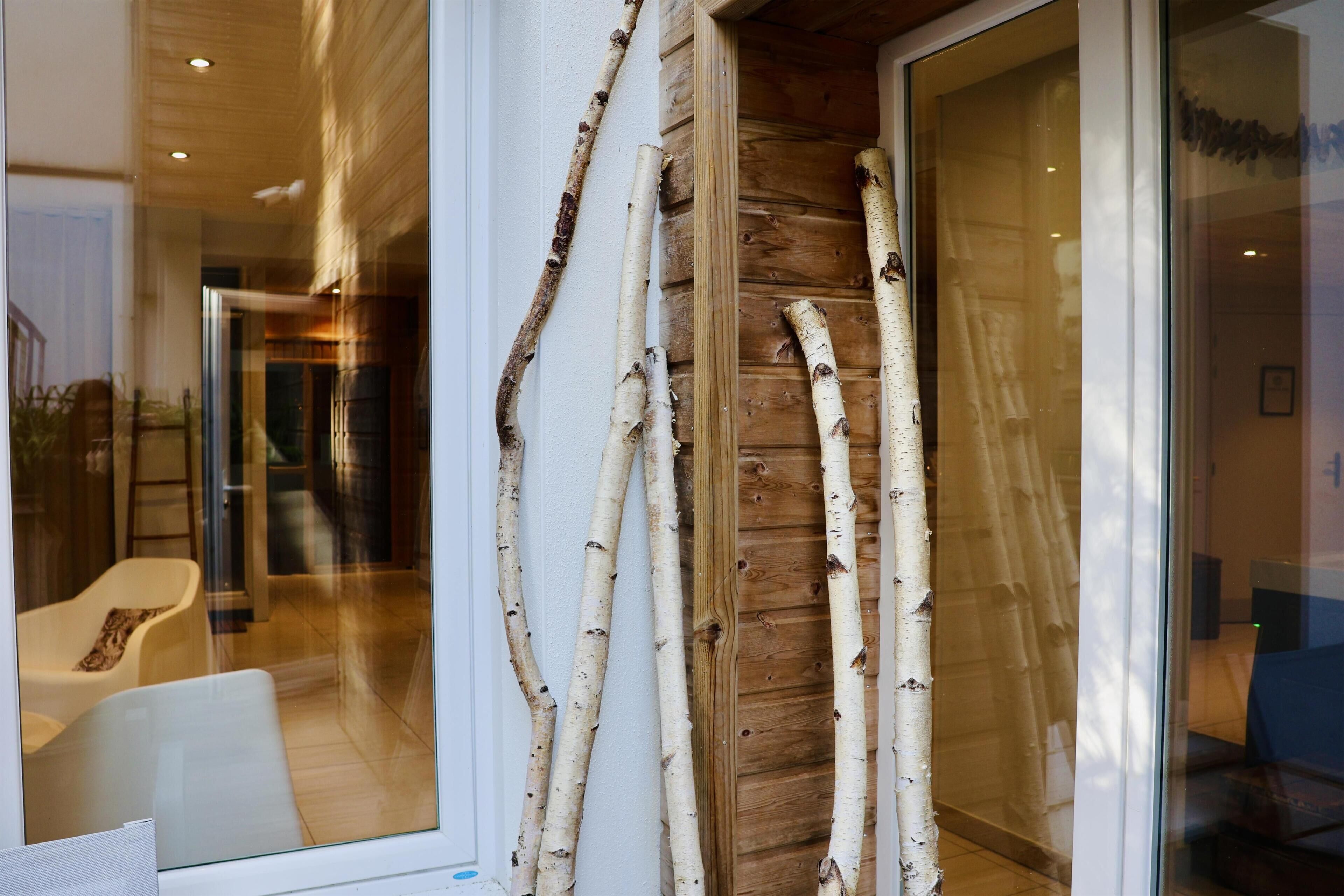 Un intérieur moderne avec des portes en verre, des murs en bois et un espace salon avec des fauteuils.