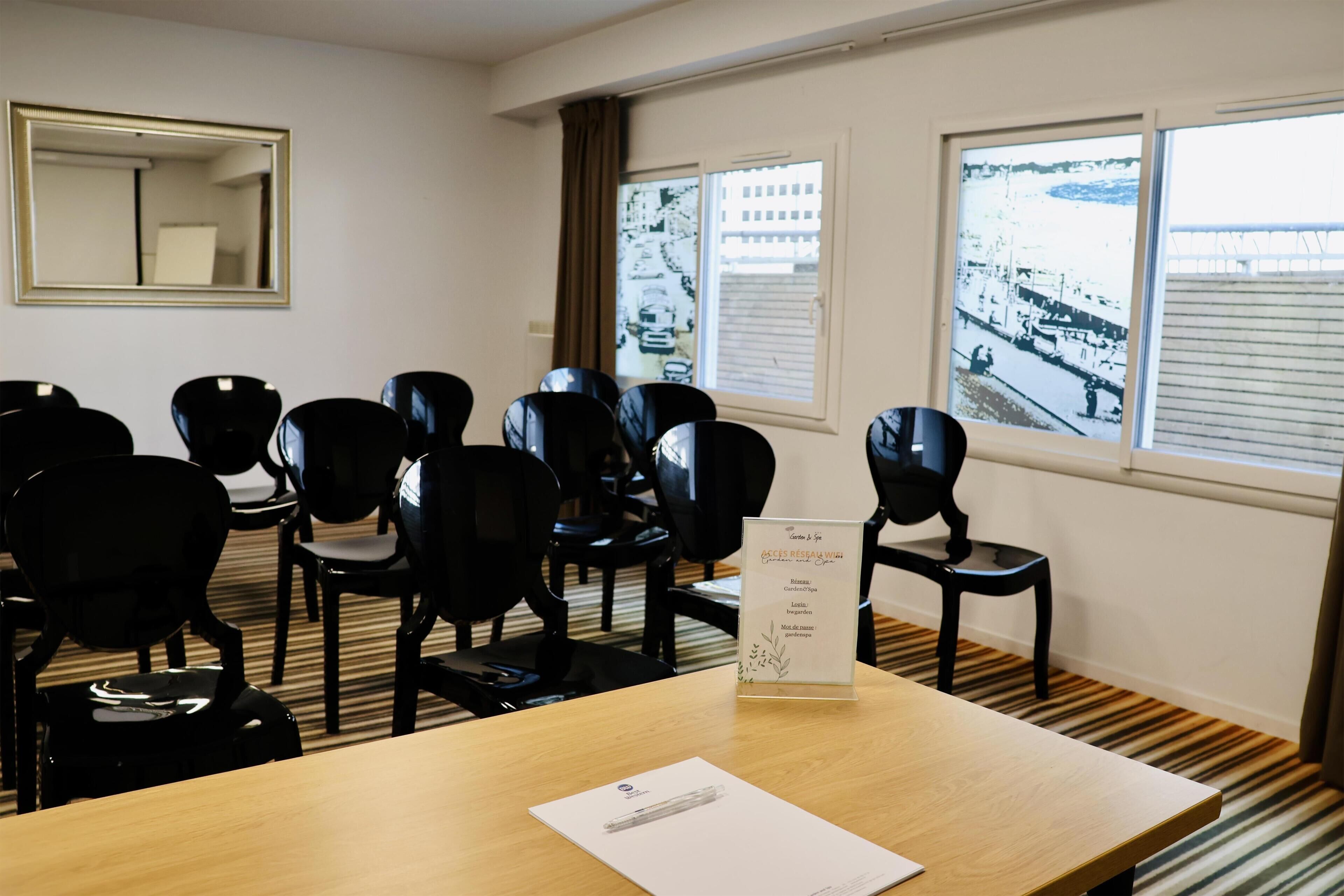 A conference room with a wooden table, black chairs, a whiteboard, and a window with a view of a bridge and buildings.