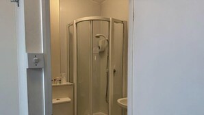A compact bathroom with a glass-enclosed shower, a toilet, and a sink. -  Deincourt Hotel (Newark)