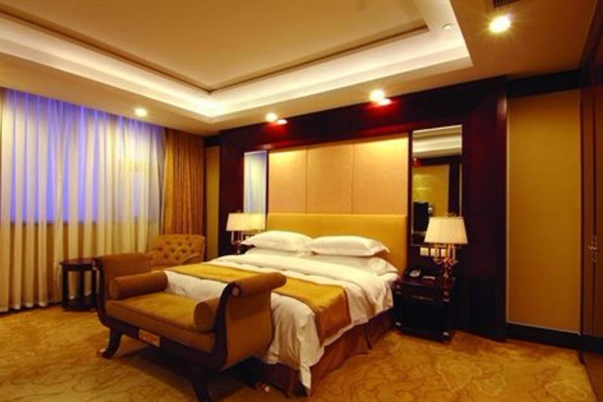 Una habitación de hotel con una cama grande, un sofá, una mesita de noche y un espejo.