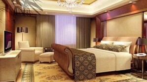 Habitación de hotel con una cama grande, un escritorio, una silla, un televisor y una araña.