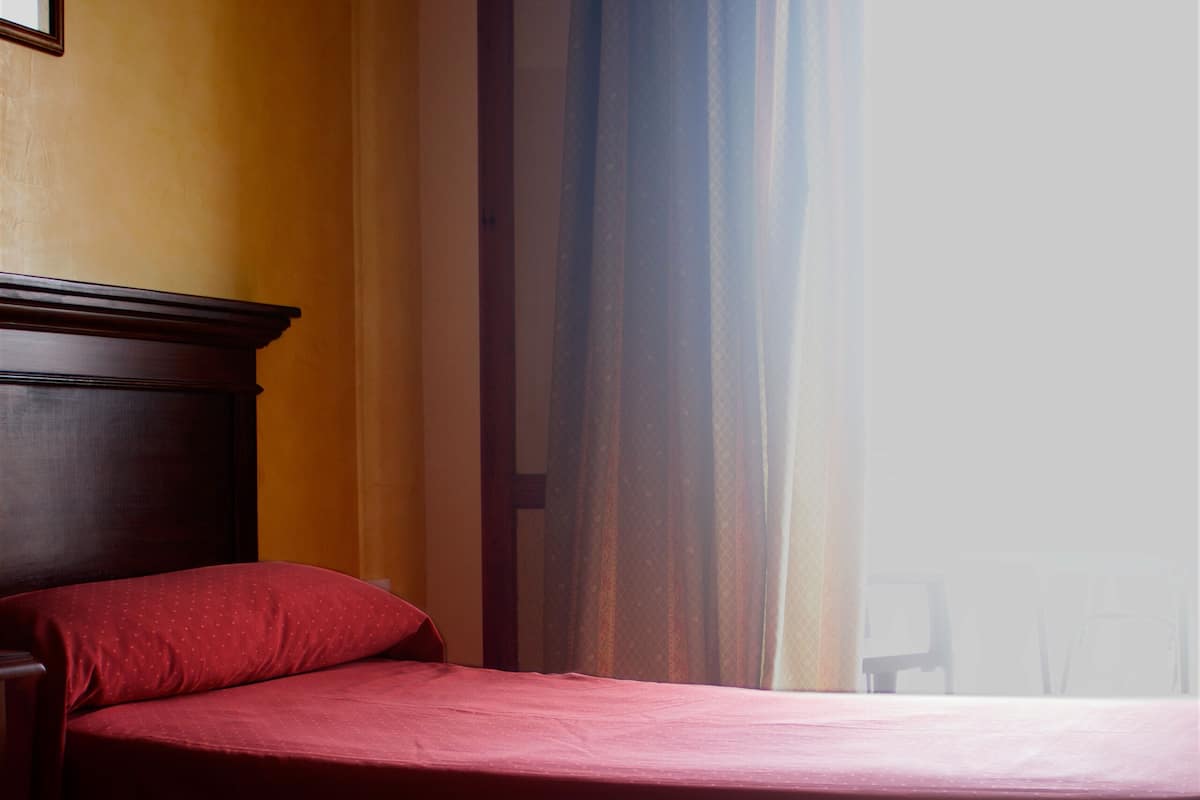 A hotel room with two beds, a wooden headboard, and a window with curtains.