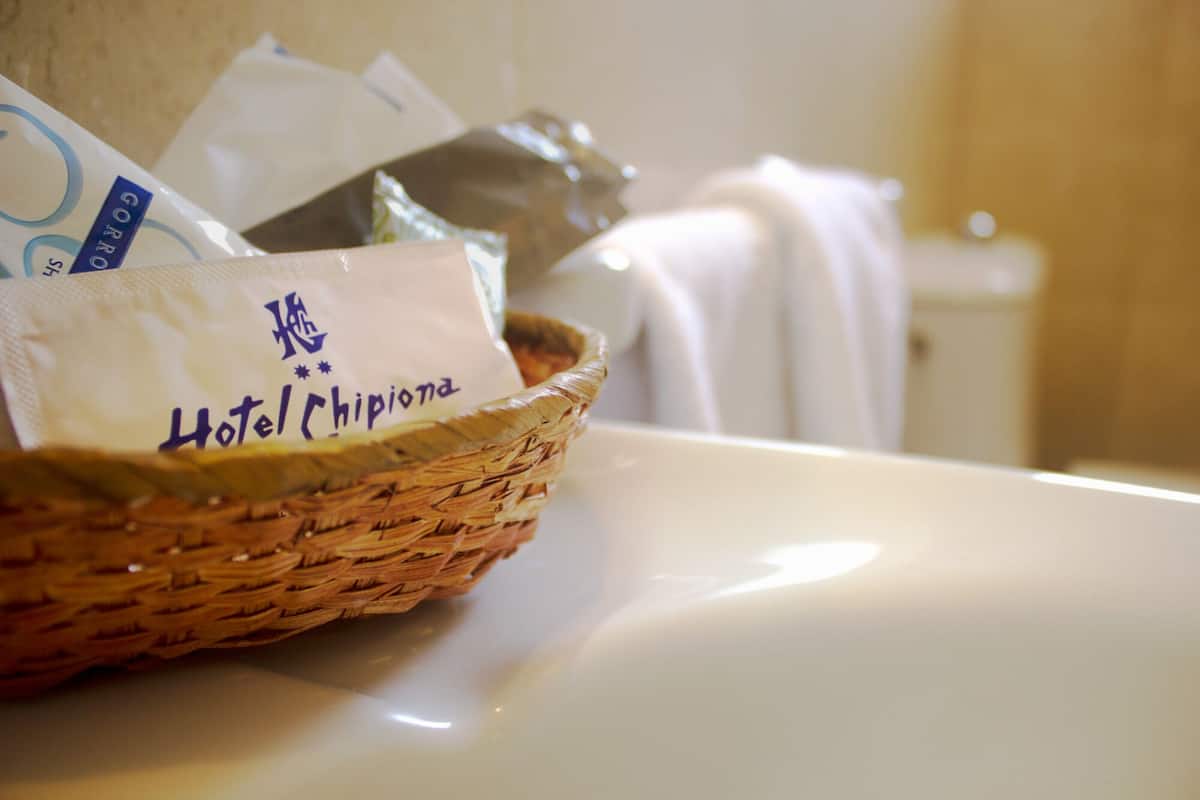 A wicker basket on a bathroom counter with a white towel and a hotel tag.