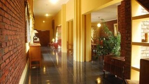 A hotel lobby with a brick wall, a reception desk, and a seating area with chairs and tables. - Bluewater Guesthouse (Gqeberha (Port Elizabeth))