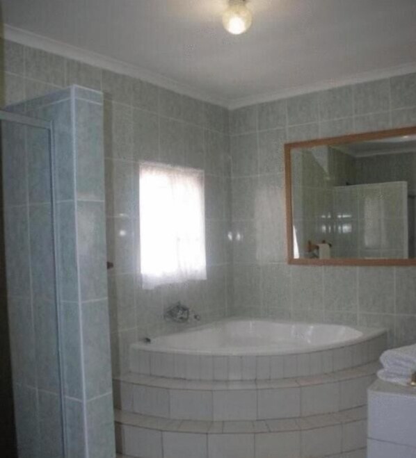 A bathroom with a bathtub, a shower, and a mirror. - Bluewater Guesthouse (Gqeberha (Port Elizabeth))