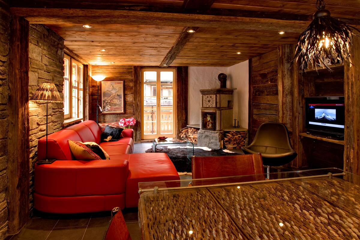 A cozy living room with a red sofa, a glass coffee table, and a television.